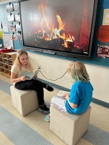 students reading next to a tv fireplace
