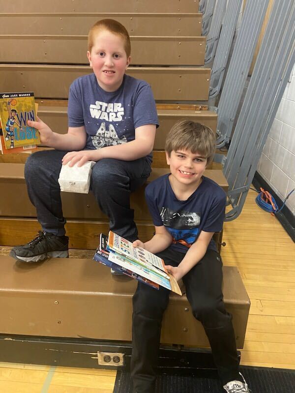 Students receiving books at a basketball game